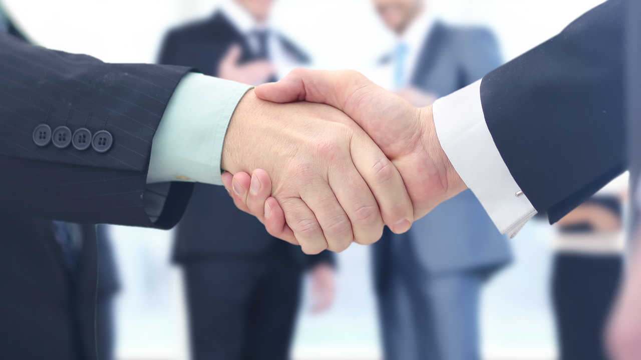 Close-up of a handshake between two businessmen in suits.