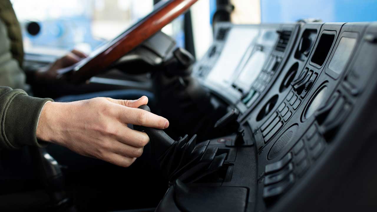 A hand on the steering wheel of a truck